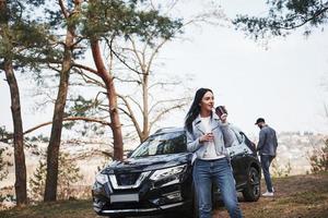 Couple have arrived to the forest on their brand new black car photo