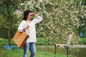 Alone in the park. Mature painter with case of instruments have a walk photo