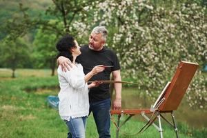 Having conversation. Mature couple have leisure days and working on the paint together in the park photo