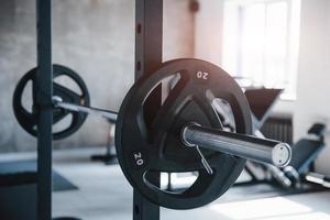 Black barbell on the metal stand in the gym at daytime. No people around photo