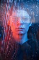 Human face behind the glass. Studio shot in dark studio with neon light. Portrait of serious man behind the wet glass photo