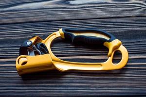 Golden colored tool. Isolated photo of climbing equipment. Part of carabiner lying on the wooden table