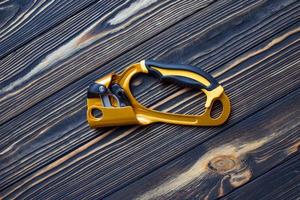 Top view. Isolated photo of climbing equipment. Part of carabiner lying on the wooden table