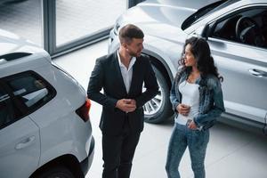 Listening carefully. Female customer and modern stylish bearded businessman in the automobile saloon photo