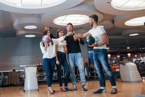 Concept of bro fist. Young cheerful friends have fun in bowling club at their weekends photo