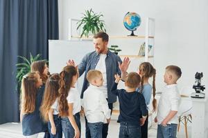 Giving high fives at the end of the lesson. Group of children students in class at school with teacher photo