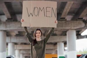 Standing alone. Pretty girl in casual clothes with handmade feminist poster in hands photo