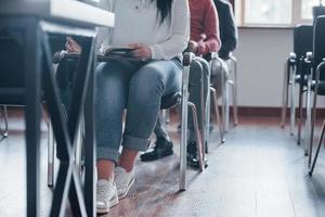 Students seating on the chairs. Group of people at business conference in modern classroom at daytime photo