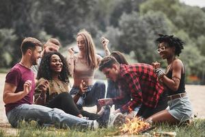 Card game. Group of people have picnic on the beach. Friends have fun at weekend time photo