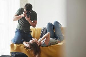 relájate y cálmate por favor. fotógrafo tomando una foto de una joven que yacía en el sofá blanco