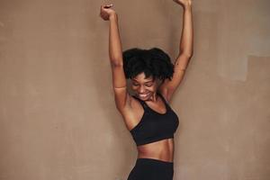 Happy girl. Young beautiful afro american woman in the studio against brown background photo