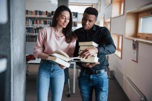 hermosos jóvenes. estudiantes multirraciales en la biblioteca buscando la información juntos foto