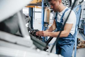 Almost done. Employee in the blue colored uniform works in the automobile salon photo