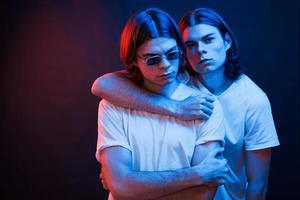 la familia es muy importante. retrato de hermanos gemelos. foto de estudio en estudio oscuro con luz de neón