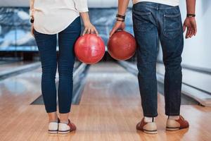 Backing view of man and girl standing with bowl balls in hands in the club photo
