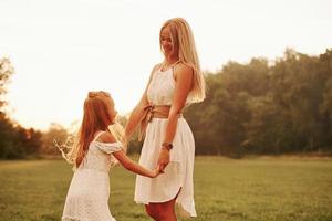 It's weekend time, let's dance. Mother and daughter enjoying weekend together by walking outdoors in the field. Beautiful nature photo