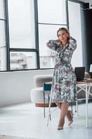 Grabbing hair to the back. Businesswoman standing in room against window photo