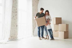 Standing together and embracing. Playful mood from the kid. Family have removal into new house. Unpacking moving boxes photo