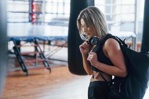 On the way to the gym. Adult female with black bag and headphones photo