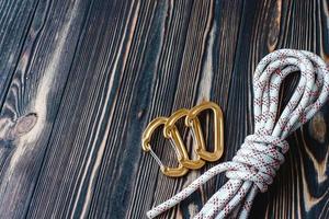 No people. Isolated photo of climbing equipment. Part of carabiner lying on the wooden table