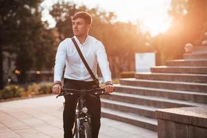 After work. Businessman in formal clothes with black bicycle is in the city photo