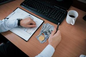 vista superior de dinero y bitcoin. hombre que trabaja en línea en la oficina con múltiples pantallas de computadora en gráficos de índice foto