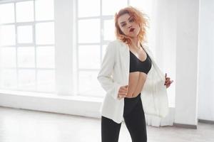 Feels the passion. Attractive redhead woman posing in the spacey room near the window photo
