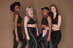 Friendly support. Group of multi ethnic women standing in the studio against brown background photo