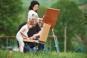 Changing colors. Grandmother and grandfather have fun outdoors with granddaughter. Painting conception photo