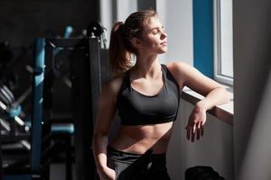 Leaning on the windowsill. Photo of gorgeous blonde woman in the gym at her weekend time