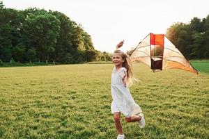 Awesome to be here. Happy girl in white clothes have fun with kite in the field. Beautiful nature photo