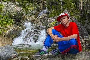 un hombre vestido de colores frescos posando frente al río noruega. foto