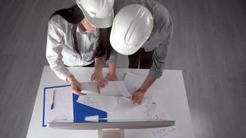 Engineers in white helmets, working on a project. Two engineers working on a project at work. One is female and one is male. video