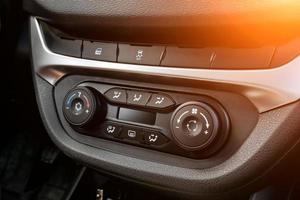 The central control console on the panel inside the car close-up with climate control and audio system and a hole for the CD and emergency button in gray and black. photo