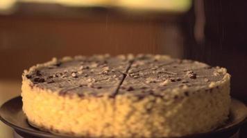 geschnittener Kakaokuchen. Szene, in der Puderzucker auf einen Kuchen gestreut wird. video