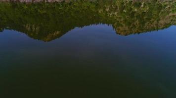 floresta e montanha refletidas no lago. o lago entre as montanhas e o reflexo das nuvens no lago. video
