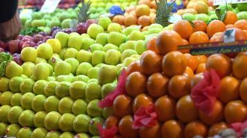 laranjas, maçãs e outras frutas. lojistas estão colocando maçãs no corredor. laranjas e maçãs verdes se destacam. video