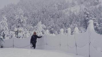 ragazzo felice che cammina nella neve. il ragazzo che cammina prepotentemente sulla strada innevata gioca con la neve da un lato. buonumore. video