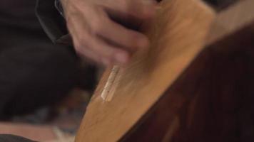 autentico strumento-baglama. primo piano del dito su un'ancia splendidamente illuminata eseguita da un giovane. suonare uno strumento a corda. suonare il basso. video