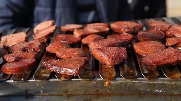 saucisse turque sur le barbecue. les tranches de saucisses sont frites au barbecue. l'huile éclabousse. saucisse turque. video