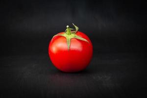Red cherry tomato isolated on black photo