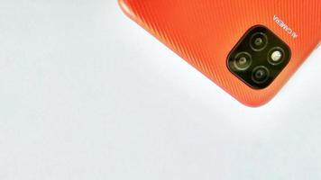 Cirebon Indonesia, April 2022. Orange smartphone of Redmi 9C model with Artificial Intelligence cameras isolated under white gray background. Suitable for company and industry advertising, etc. photo