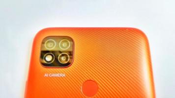 Cirebon Indonesia, April 2022. Orange smartphone of Redmi 9C model with Artificial Intelligence cameras isolated under white gray background. Suitable for company and industry advertising, etc. photo