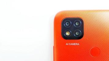 Cirebon Indonesia, April 2022. Orange smartphone of Redmi 9C model with Artificial Intelligence cameras isolated under white gray background. Suitable for company and industry advertising, etc. photo