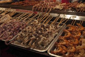 Brochetas variadas de pescado fresco y marisco. mercado callejero en china foto