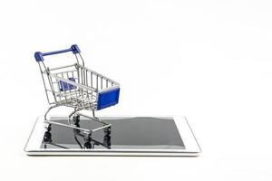 carrito de compras con tableta en backgrond blanco, significa comprar en línea foto