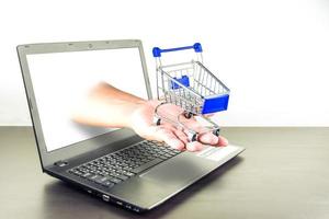 Computer notebook blank screen with shopping cart on wood table photo