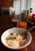 fresh Thai congee with boiled egg and pork in white bowl on wooden table photo