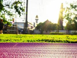 Pink yoga mat laid on green grass In the park in the evening there was a soft sunlight. The warm light tones are suitable for yoga exercises. photo