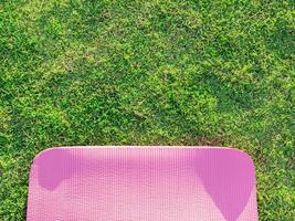 Pink yoga mat laid on green grass In the park in the evening there was a soft sunlight. The warm light tones are suitable for yoga exercises. photo